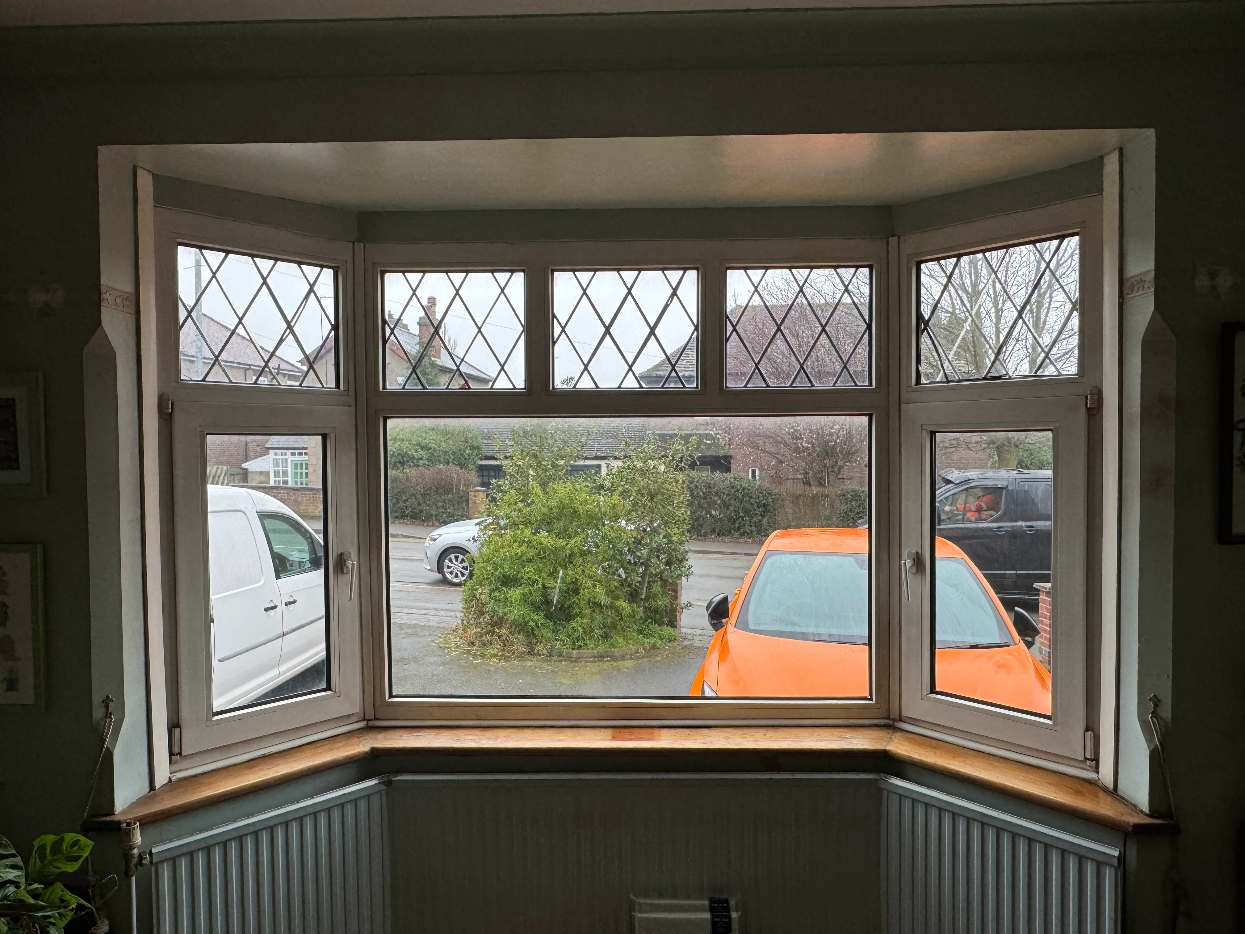Curtain pole fitted across a 1930s bay window, with curtains hung and plants on the windowsill