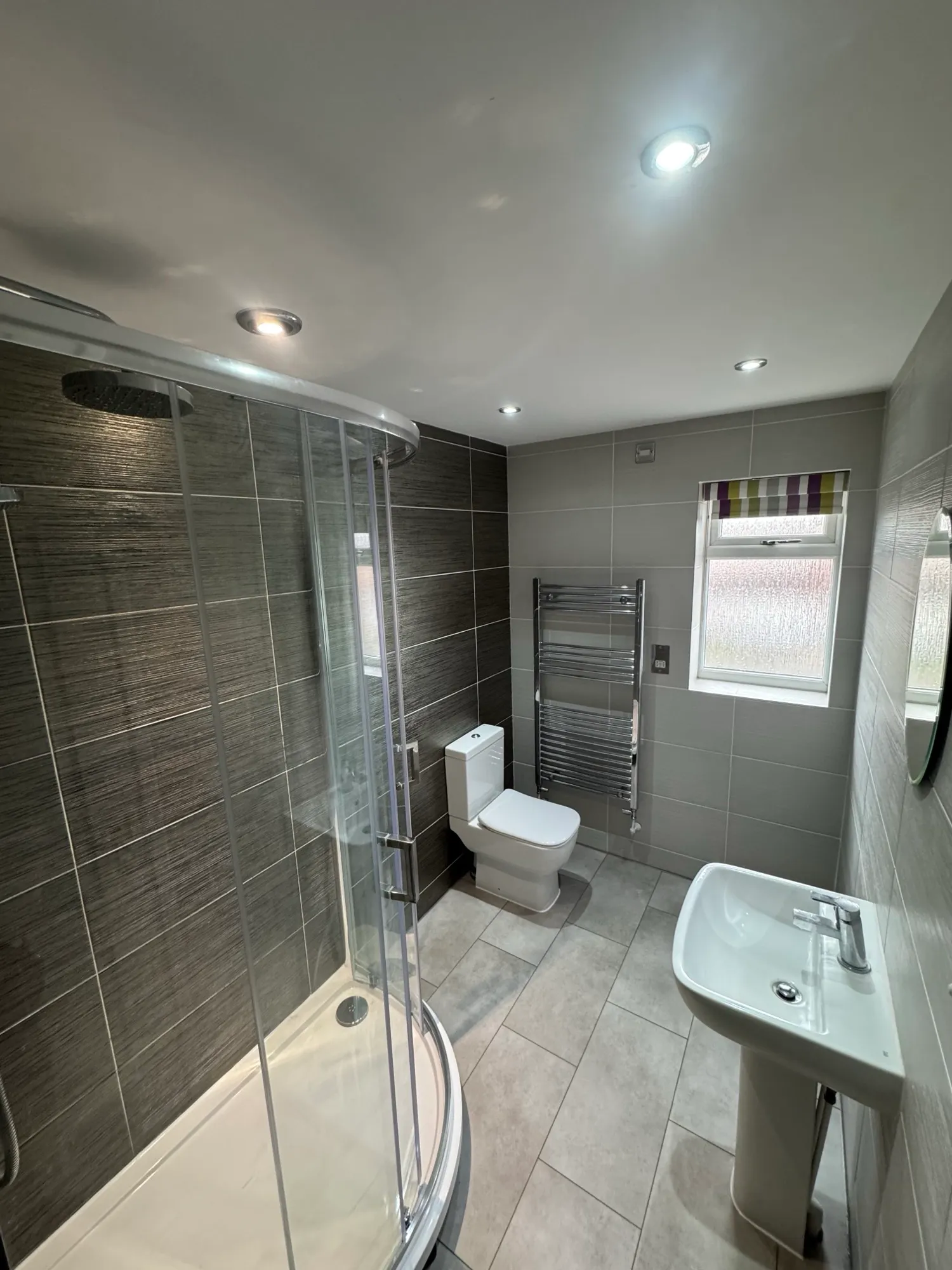 Bathroom in Swadlincote part-way through renovation, with the floor stripped back and dark tiled walls