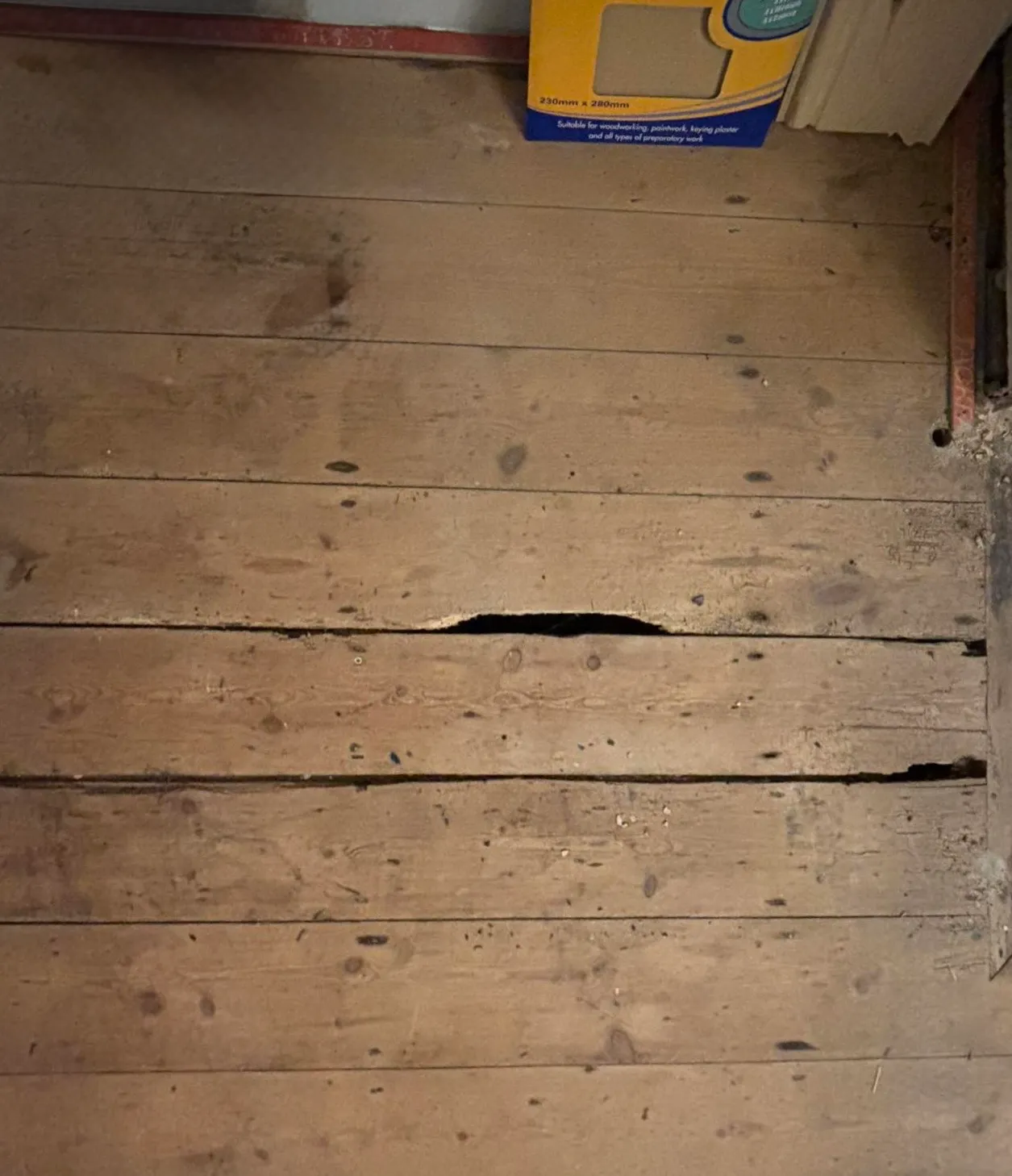 Lifted floorboards exposing the damaged section before repair